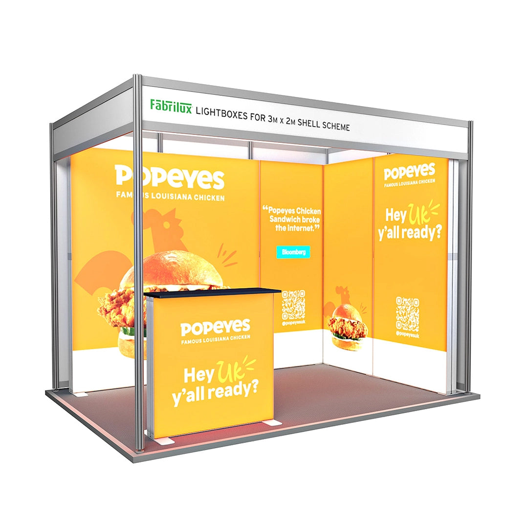 A backlit shell scheme with panels, featuring the Popeyes brand, including a counter and printed promotional materials.