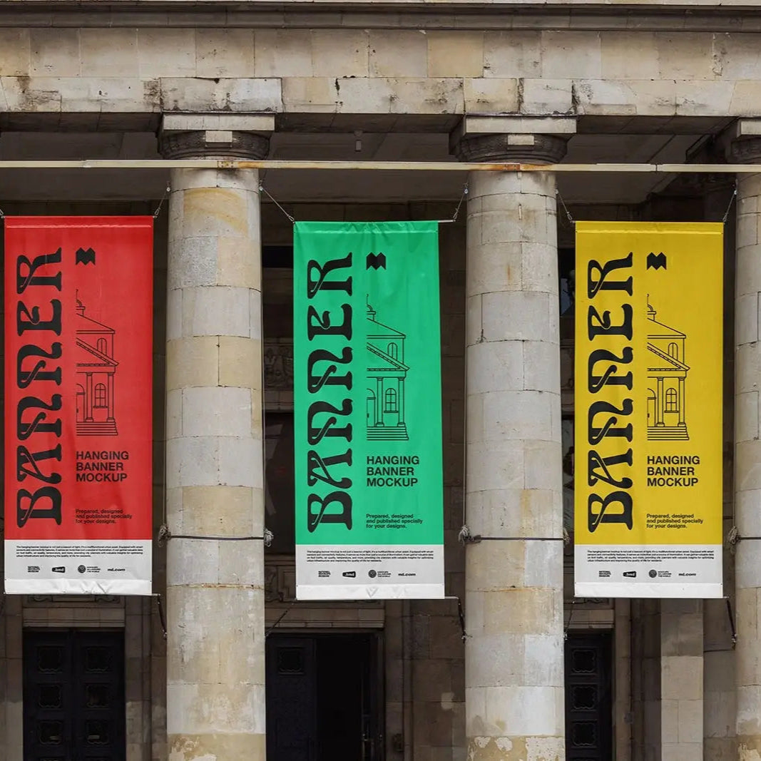 Three vertical hanging banners in red, green, and yellow displayed between stone columns on a building exterior, showcasing a hanging banner design mockup.