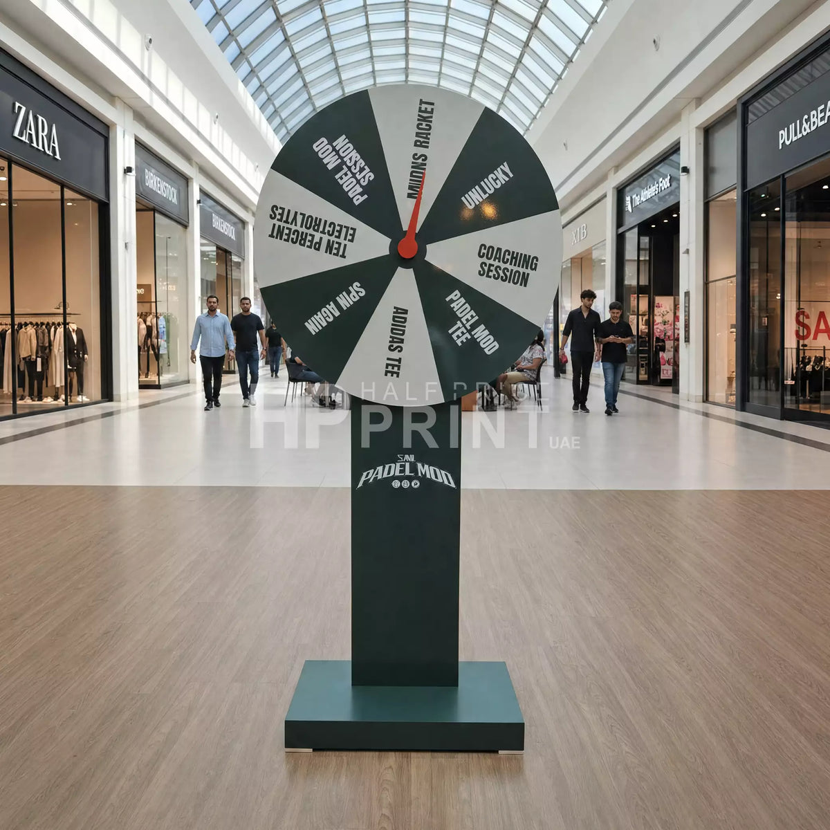 Large spinner toy in a shopping mall with various options on its sections.