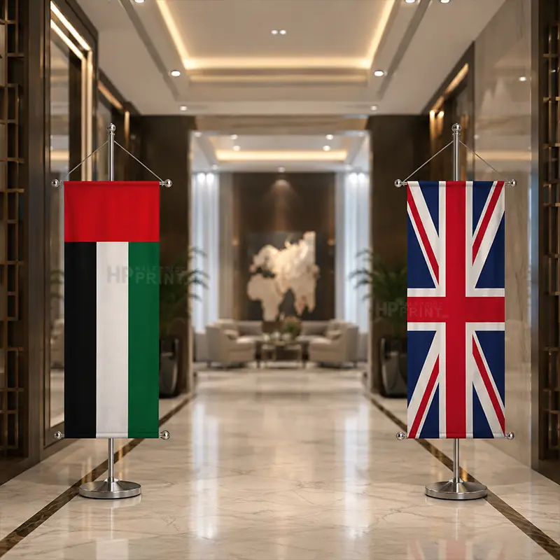 Two vertical flag banners displaying the United Arab Emirates flag on the left and the United Kingdom flag on the right, set in a modern, upscale hallway with polished marble floors and warm lighting.