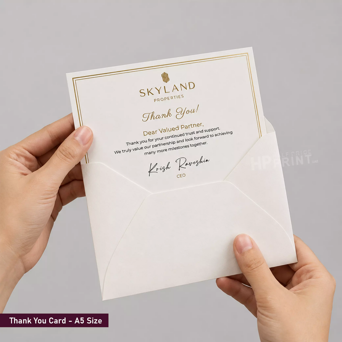 Person holding a thank you card from Skyland Properties with a gray background
