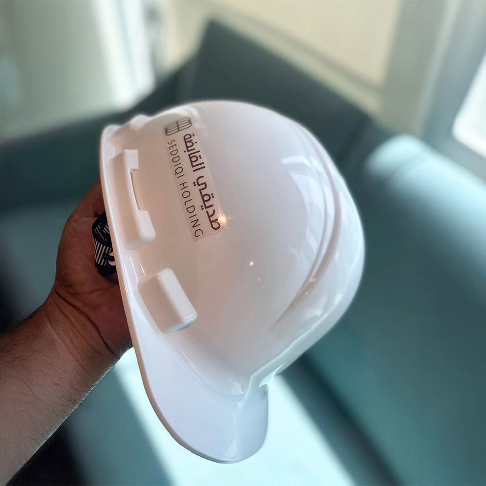 A hand holding a white custom cap with a logo printed on it.