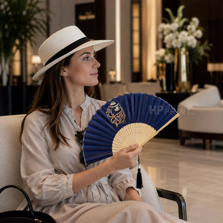 Woman holding a blue and bamboo fan in an indoor setting