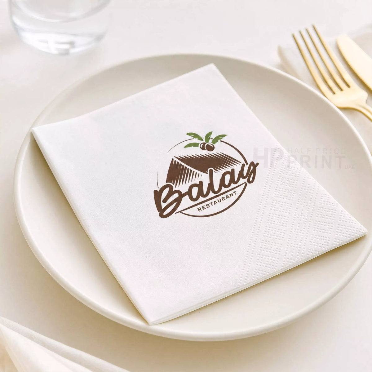 Napkin with Balau Restaurant logo on a white plate with cutlery