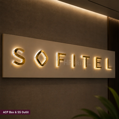 A push through sign displaying the brand name 'SOFITEL' in gold metallic letters on a rectangular light box mounted on a dark textured wall.