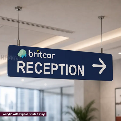 A blue rectangular hanging sign with white text reading 'britcar RECEPTION' and a white right-pointing arrow, suspended from the ceiling in an indoor office or lobby setting. A small logo appears on the left side of the sign.