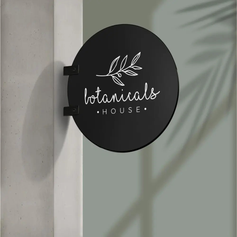 Round black sign with 'botanicals house' text and leaf design on a light background