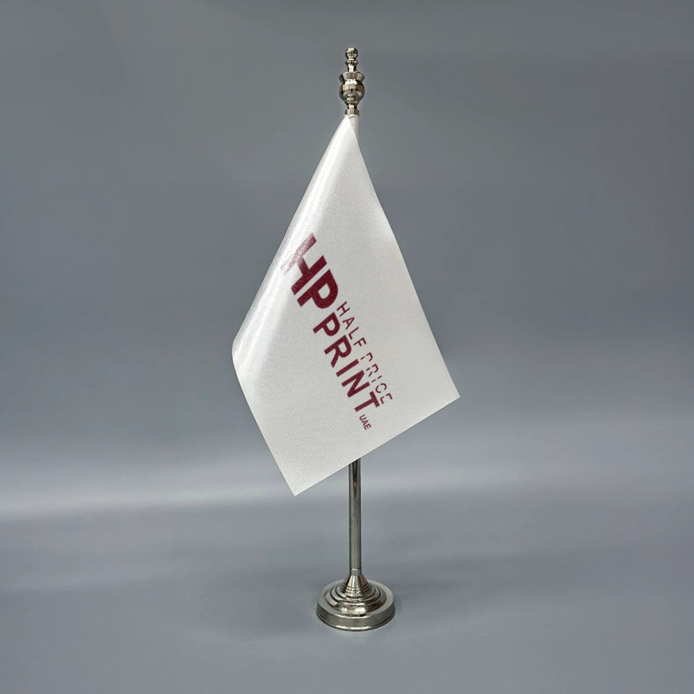 A white table flag with red text, mounted on a metal stand.