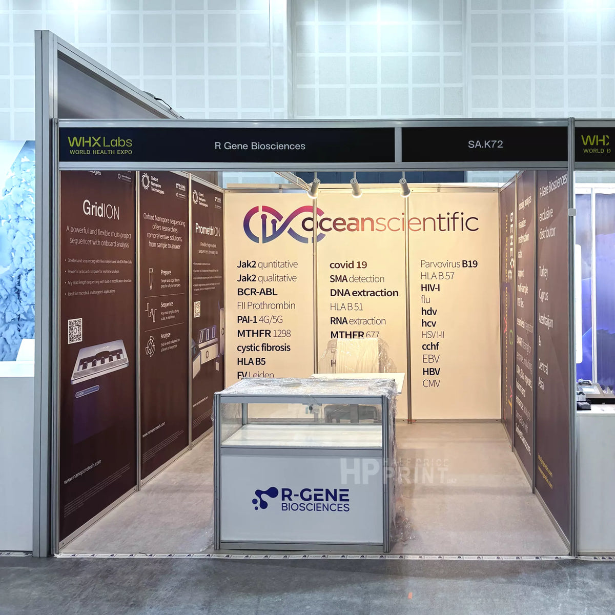 A shell scheme booth display for R-GENE Biosciences and Oceanscientific, featuring a central glass display case with the R-GENE logo, brown and beige informational panels, and a black header sign.