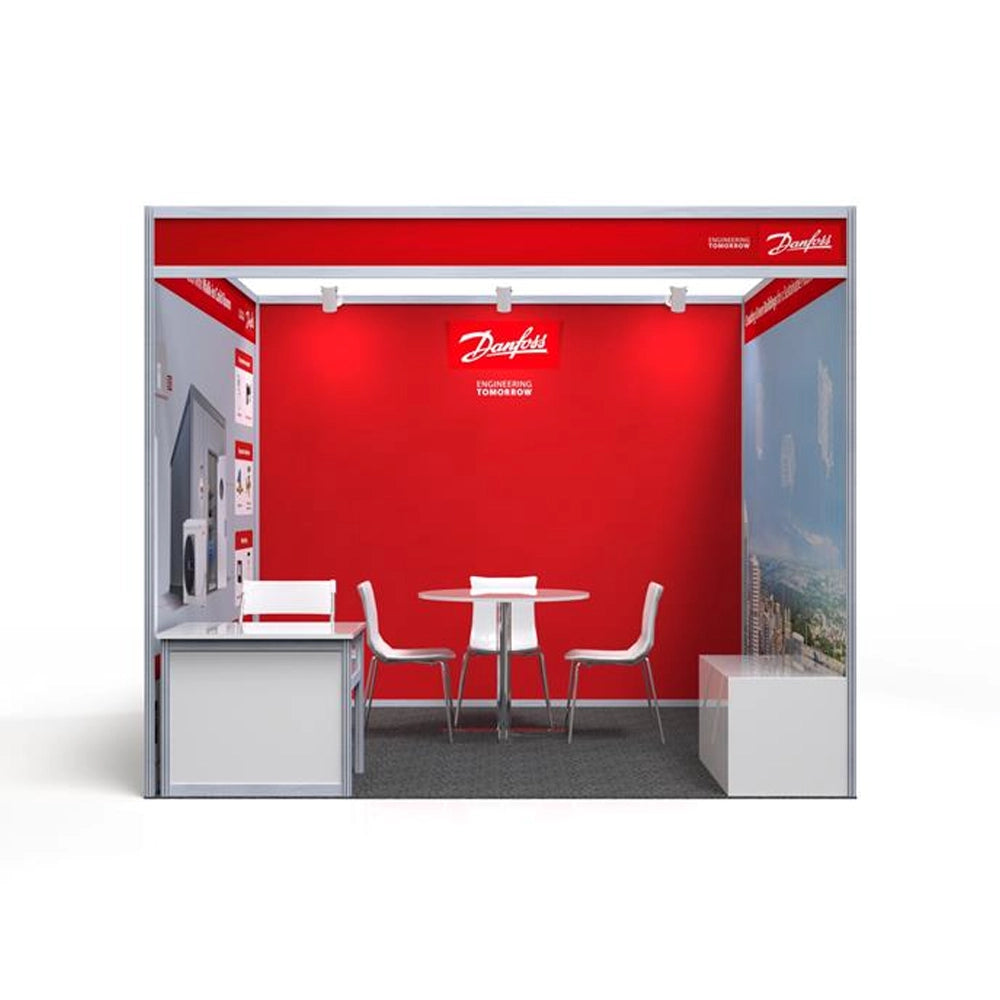 A red and white exhibition stand with a large logo on the top, a table, two chairs, and a counter.