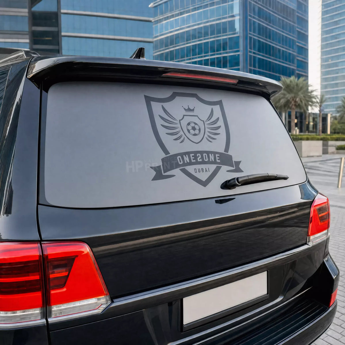 Black car with a logo decal on the back, parked in an urban setting.