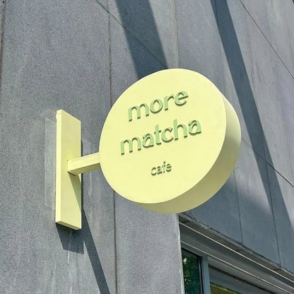 Yellow sign with 'more matcha cafe' on a gray building