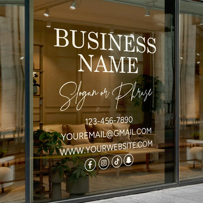 Storefront window displaying a vinyl decal with a business name, slogan, phone number, email address, website, and social media icons, applied to a modern interior shop window.